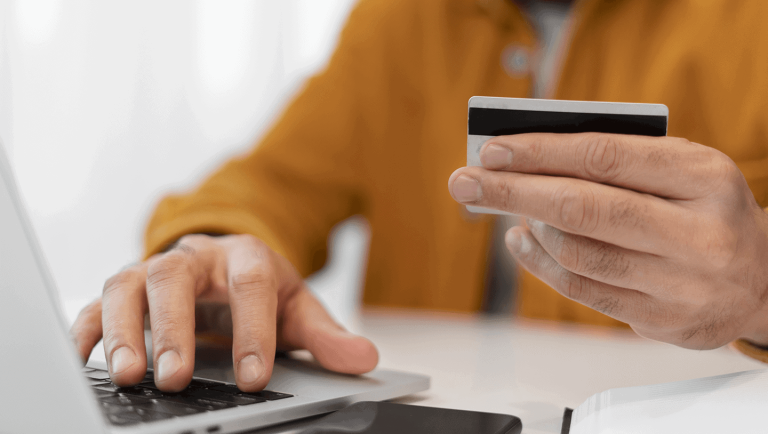 Person holding a credit card while paying an invoice on a laptop
